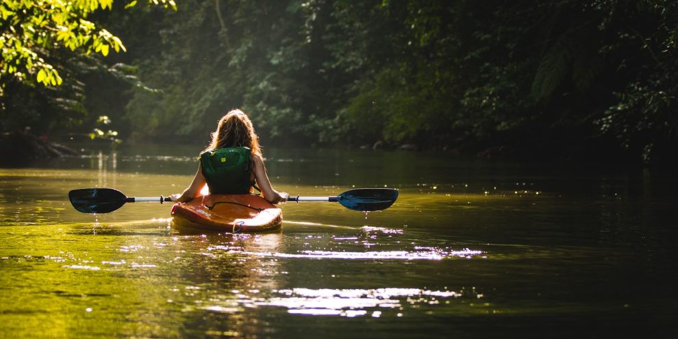 woman on kayak on body of water holding paddle