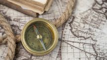 A close-up of a vintage compass on an antique world map, depicting navigation history.