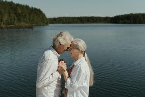 Senior couple in love sharing a tender moment by a tranquil lakeside.
