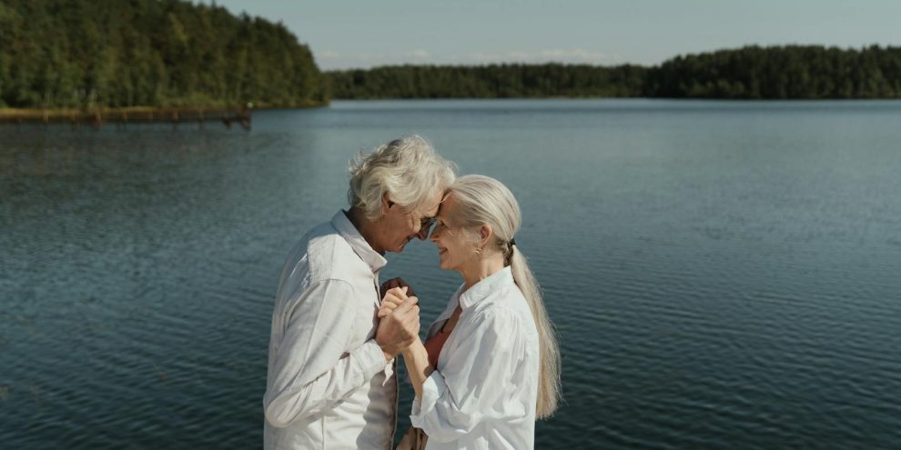 Senior couple in love sharing a tender moment by a tranquil lakeside.