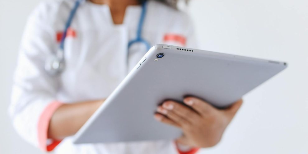 Close-up of a doctor wearing a mask using a tablet for healthcare management.